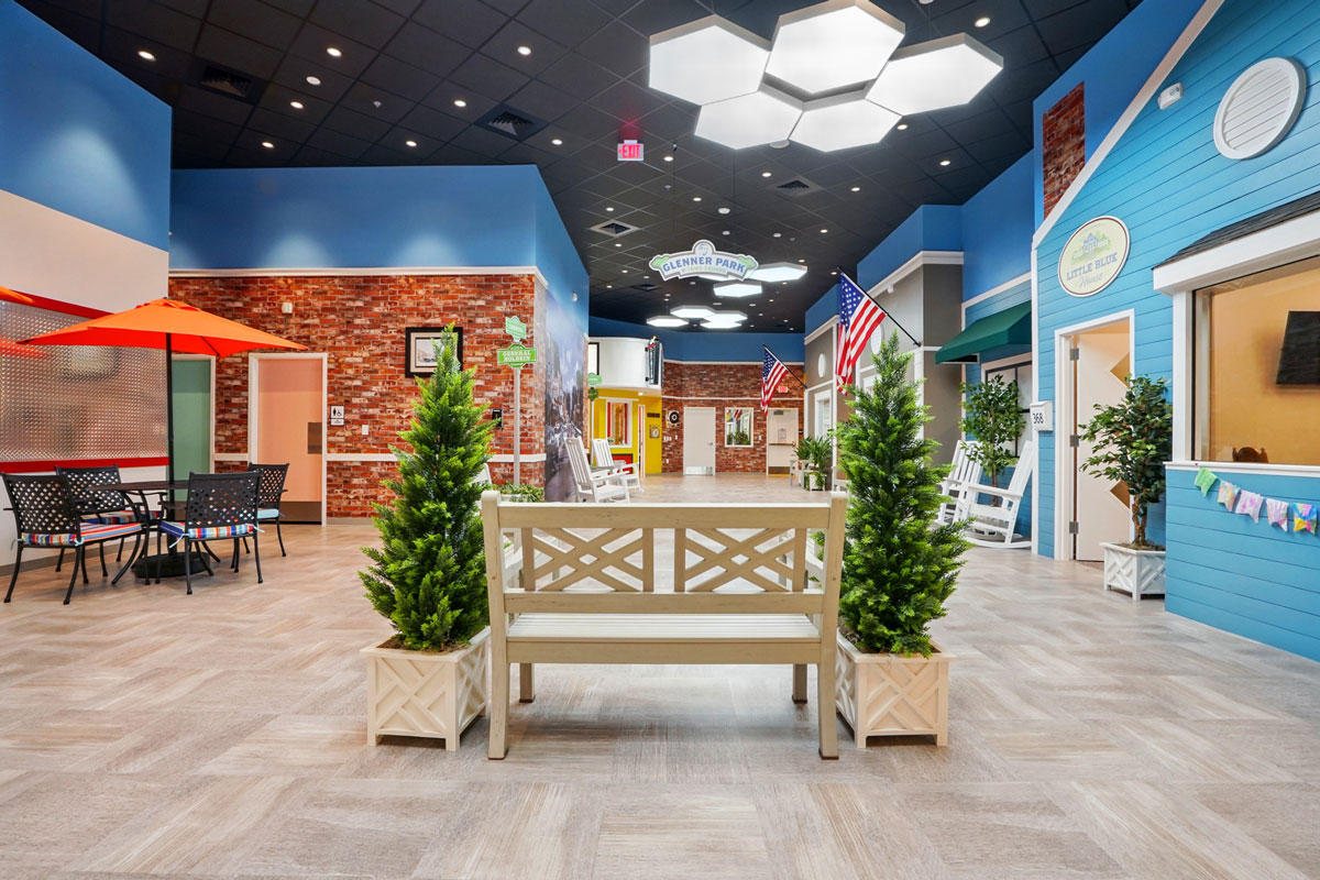Indoor community space designed like a small town with colorful storefronts, American flags, and seating areas.